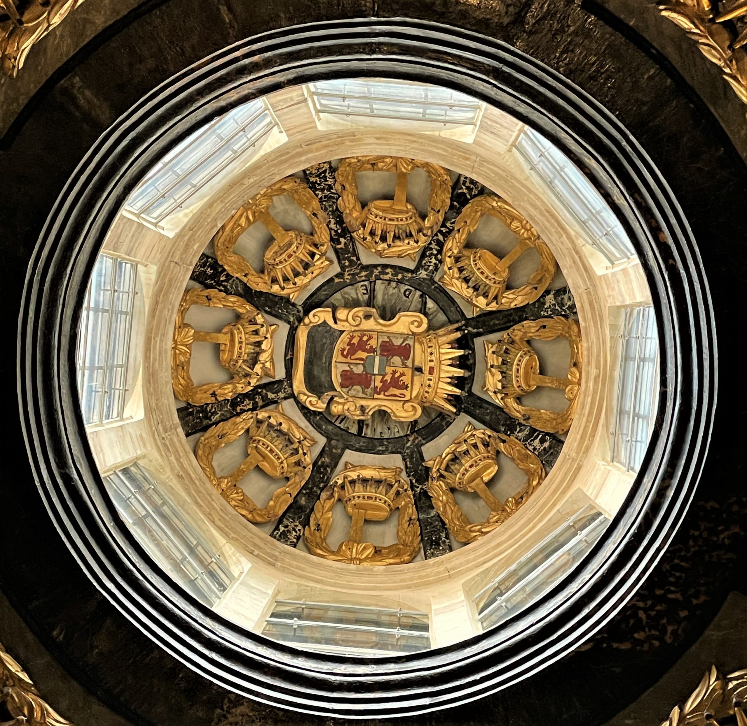 Coupole au plafond décorée de motifs dorés et armoiries.